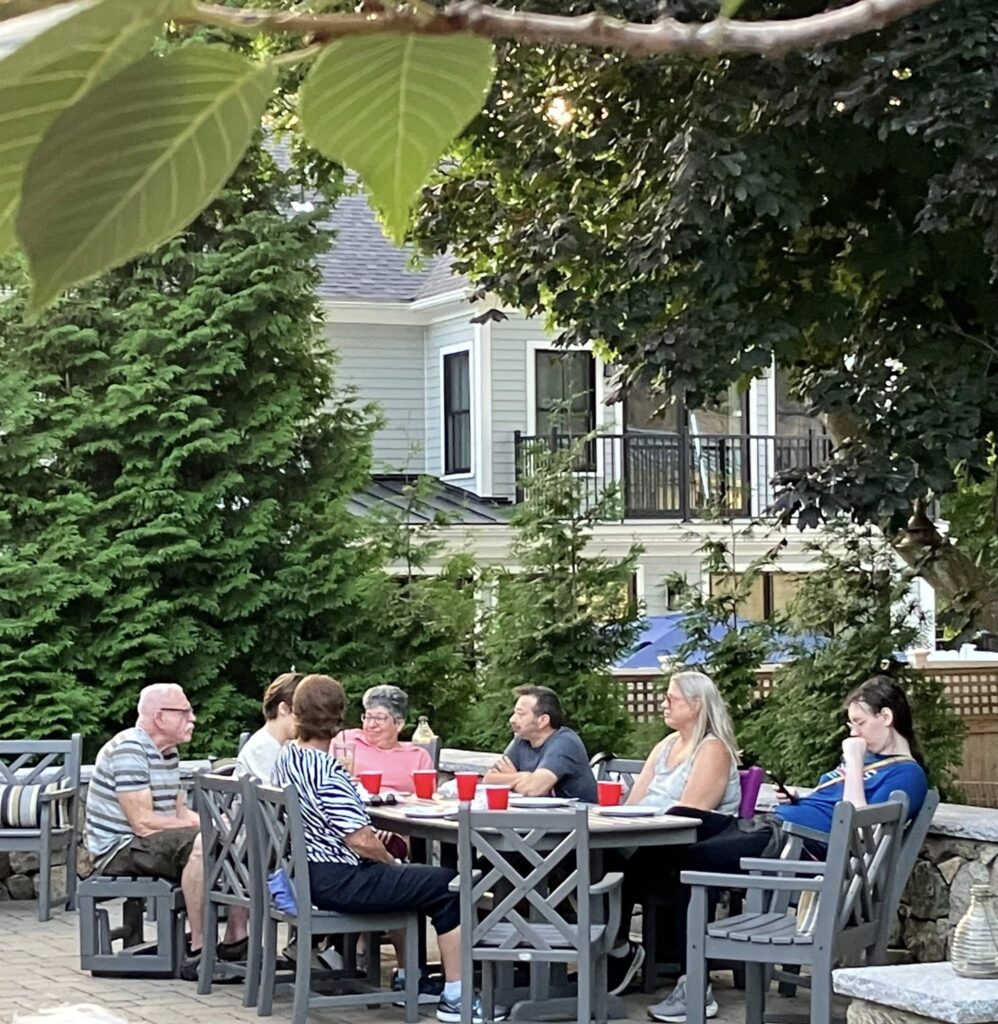 members gathered around the table outside for a BBQ