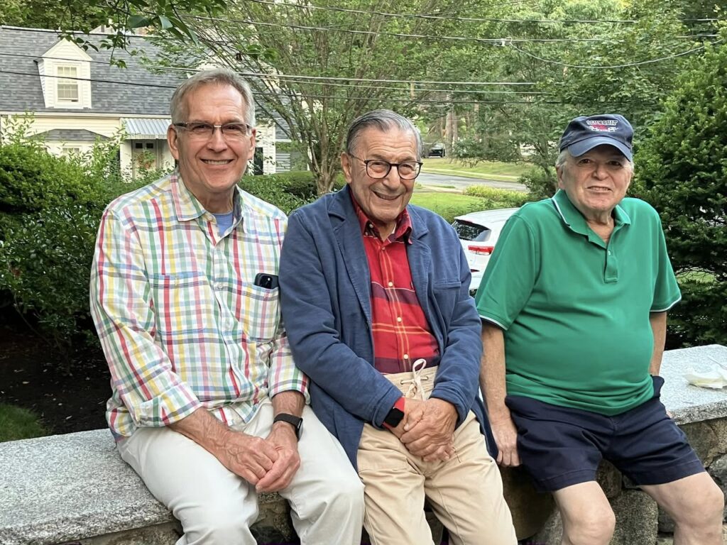 three members sitting on a wall outside