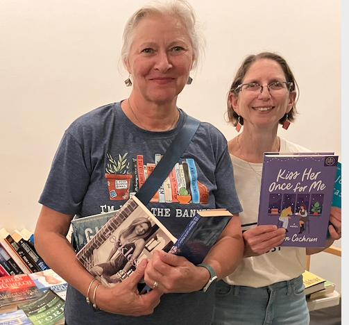 photo of two women posing with armfuls of books