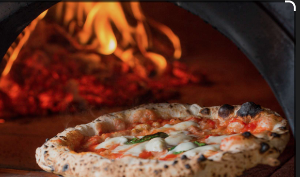 pizza in front of a brick oven pizza